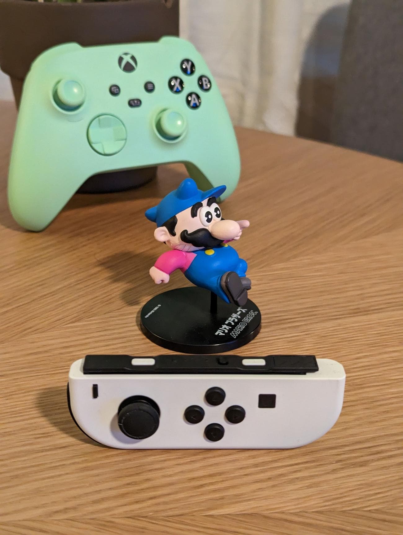 Μια φωτογραφία ενός ειδωλίου Super Mario και δύο χειριστηρίων παιχνιδιών, τραβηγμένη με zoom 2x.