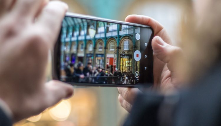Image of a man's hands holding an Android phone recording video