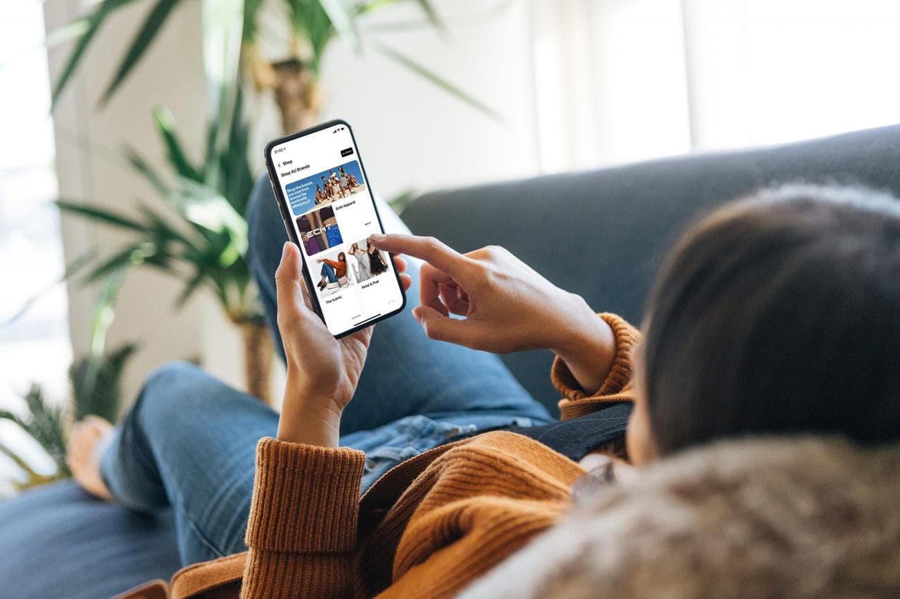 Μια γυναίκα ξαπλώνει σε έναν καναπέ και περιηγείται στο Afterpay.