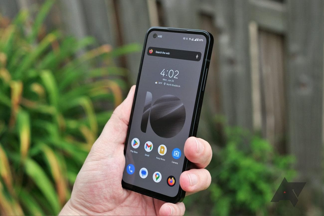 Asus Zenfone 10 held in hand at angle with screen facing camera