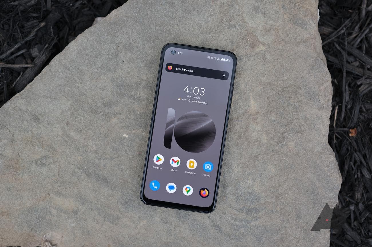 Asus Zenfone 10 resting on top of slate rock with screen on