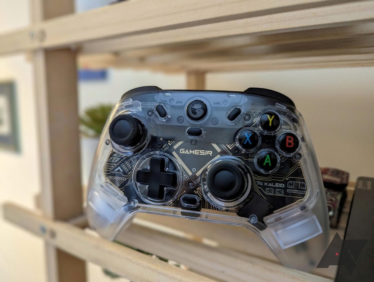 διαφανές χειριστήριο παιχνιδιών που στηρίζεται σε ξύλινο ράφι