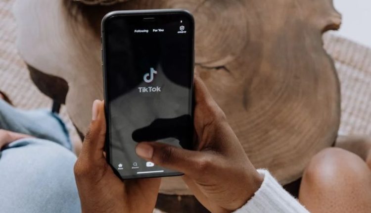 Person opening TikTok app on smartphone.