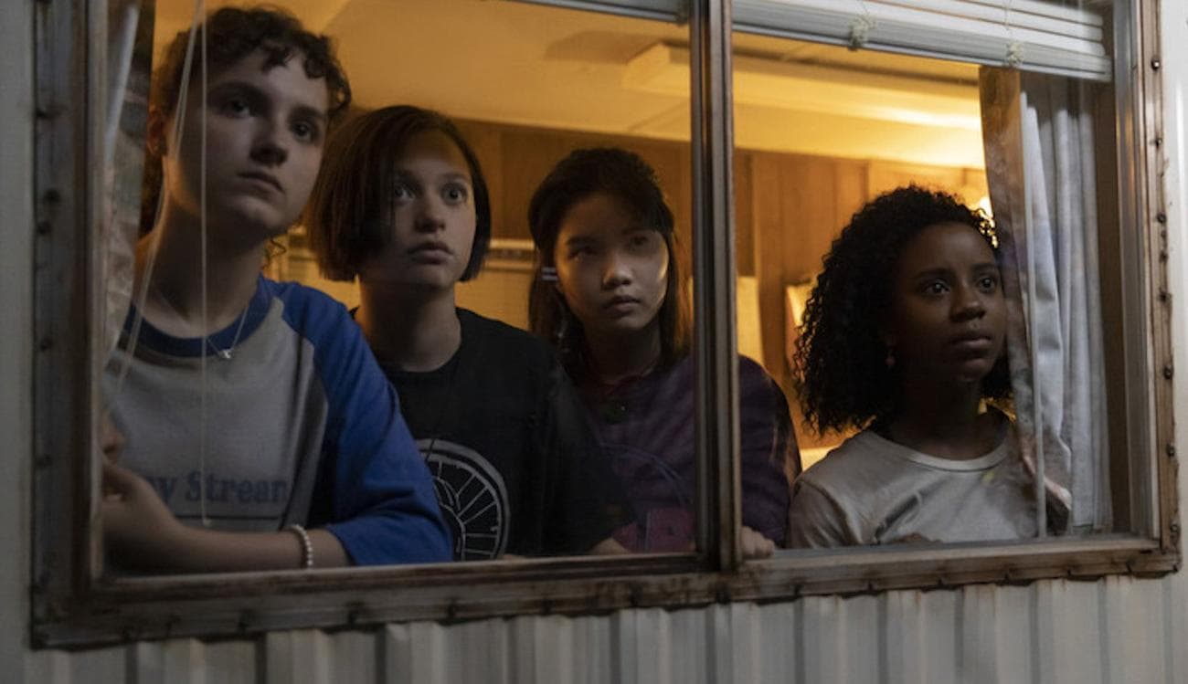 Four teens look out a window of a trailer.
