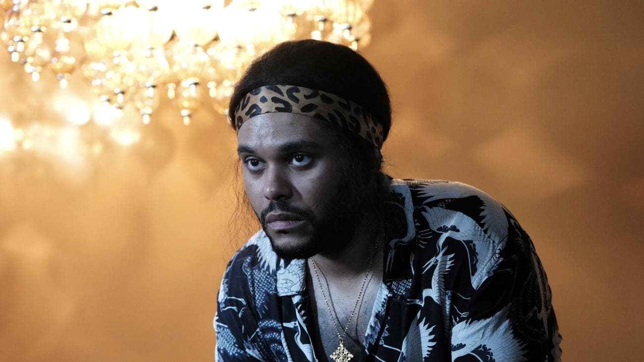 Ένας ατημέλητος άντρας σε ένα ράτσαλ σε ένα δωμάτιο με έναν αναμμένο πολυέλαιο.