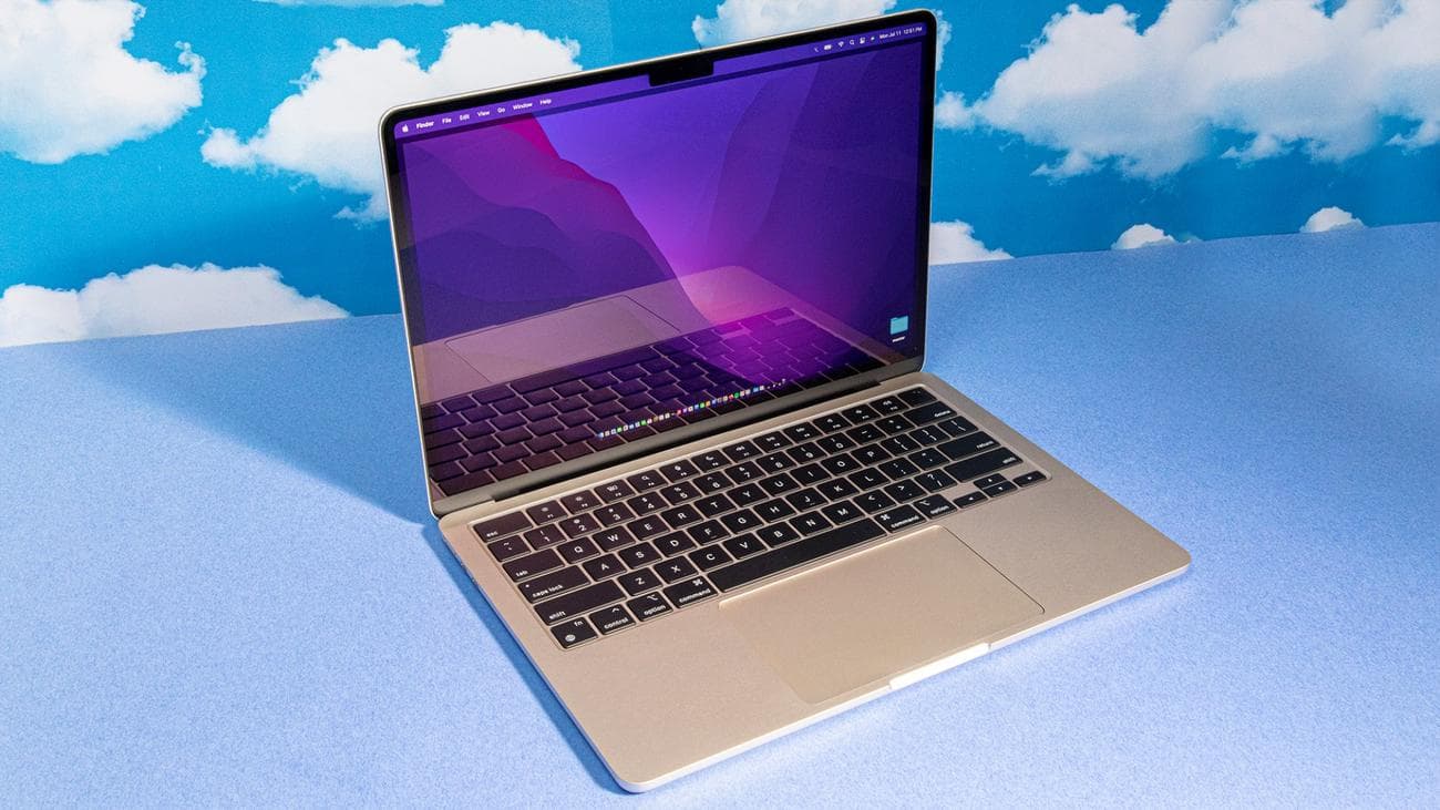 2022 M2 MacBook Air ανοιχτό και σε προβολή προφίλ σε μπλε φόντο με επαναλαμβανόμενα μοτίβα σύννεφων