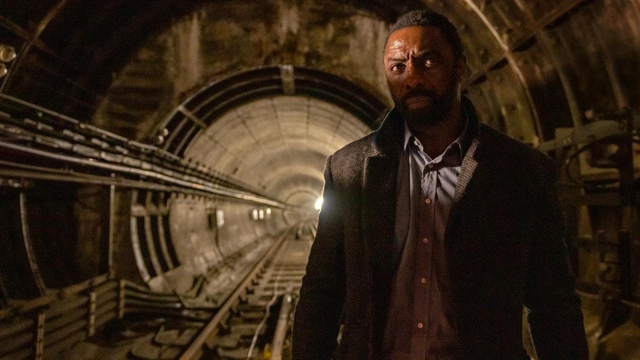 Idris Elba stands in an underground train tunnel in the film 