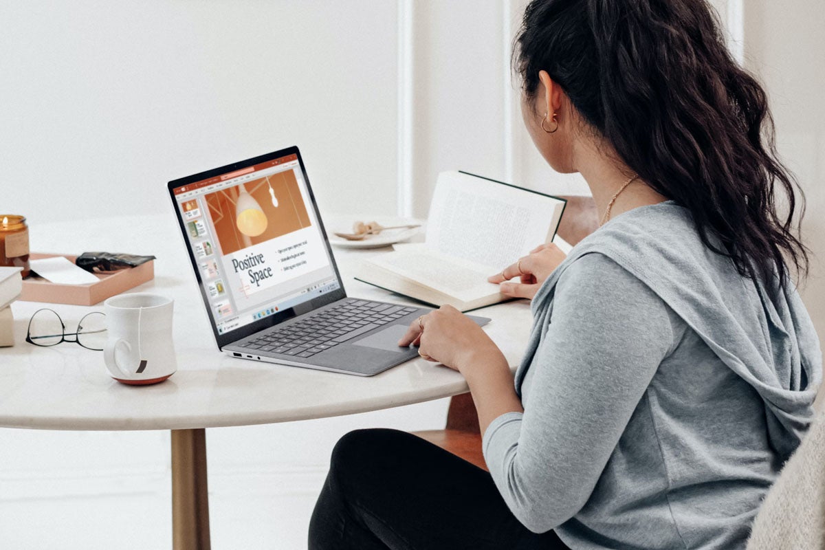 A person using Microsoft Office on a laptop and sitting at a table