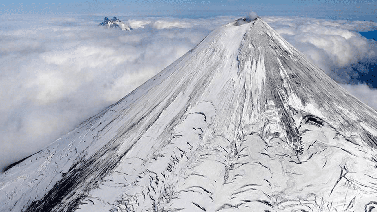 Aerial view of Shishaldin Volcano with Isanotski Peaks in the background, taken from a helicopter overflight during geology field work on Unimak Island in the Aleutians. August 15, 2018.
