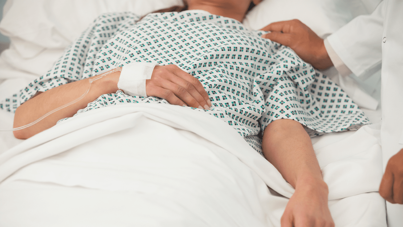 A woman in a hospital, with a doctor touching her shoulder. Some of the health problems associated with long COVID include blood clots, diabetes, heart issues, blood clots, diabetes, neurologic complications, gastrointestinal disorders, fatigue, and difficulties with mental health.