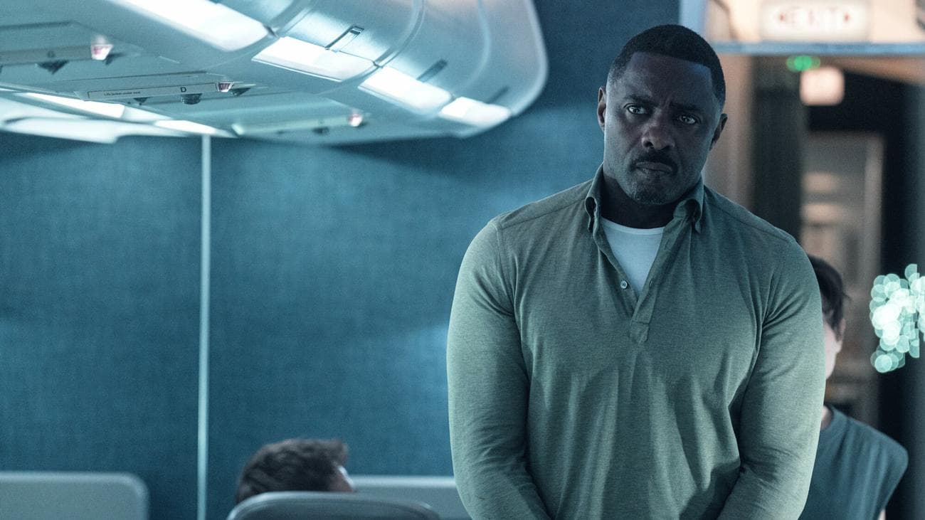 Idris Elba stands in a plane aisle looking worried in the TV show "Hijack"