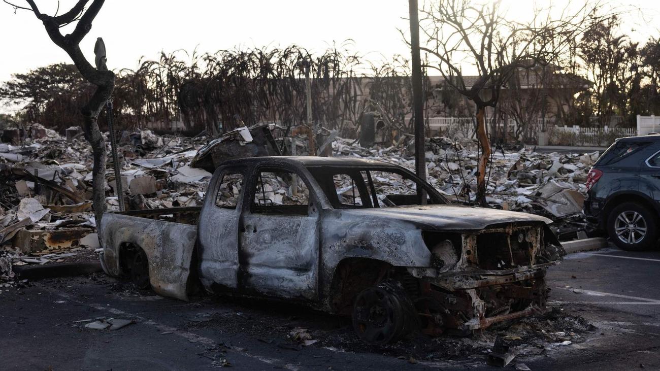 A burnt out car lies in the driveway of charred apartment complex in the aftermath of a wildfire in Lahaina, western Maui, Hawaii on August 12, 2023.