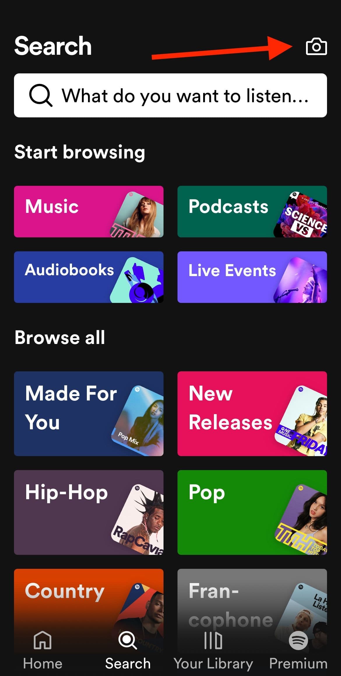 Η οθόνη αναζήτησης της εφαρμογής Spotify με ένα κόκκινο βέλος που δείχνει το εικονίδιο της κάμερας στην επάνω δεξιά γωνία.