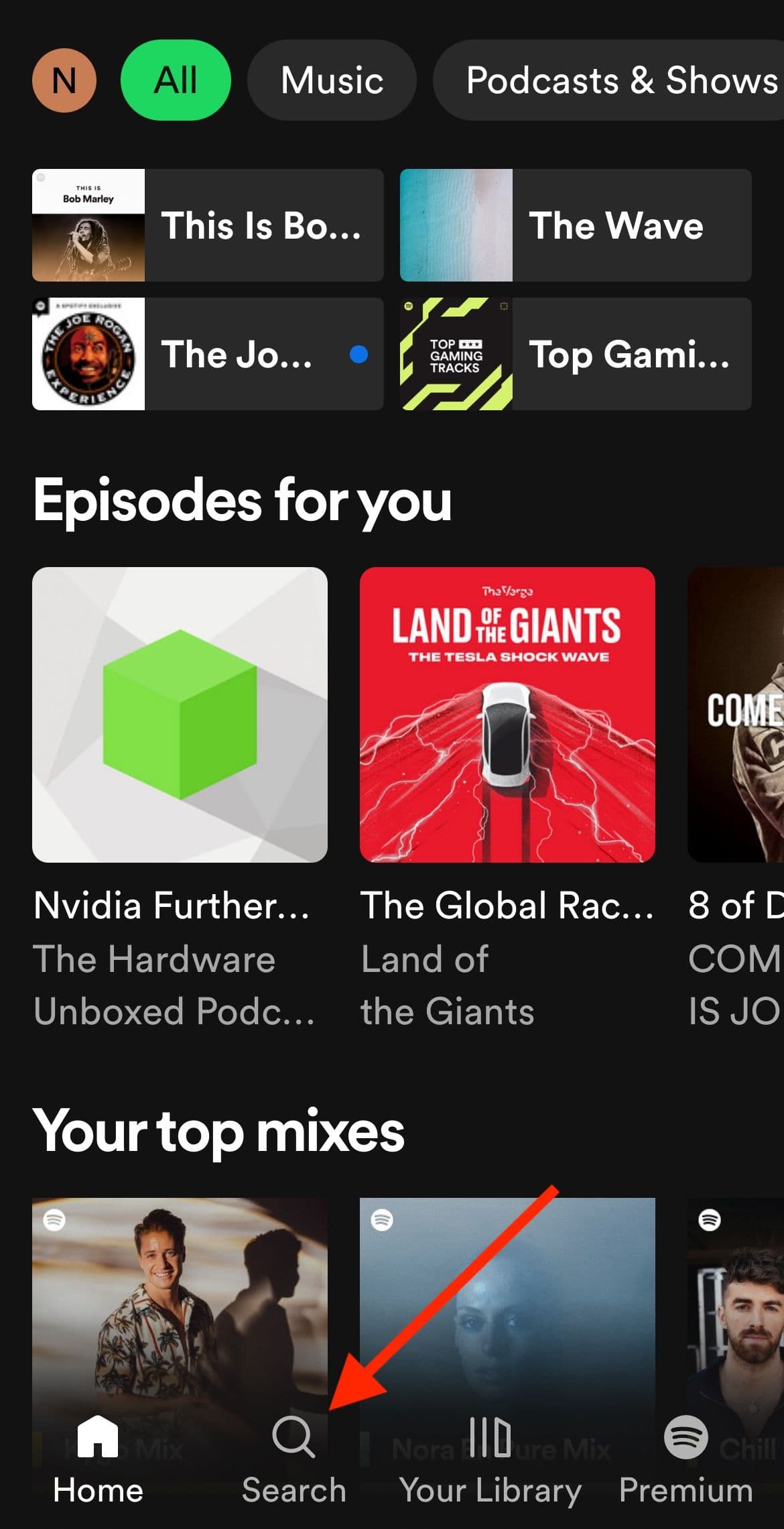 Η αρχική οθόνη της εφαρμογής Spotify με ένα κόκκινο βέλος που δείχνει τον μεγεθυντικό φακό αναζήτησης στο κάτω μέρος.