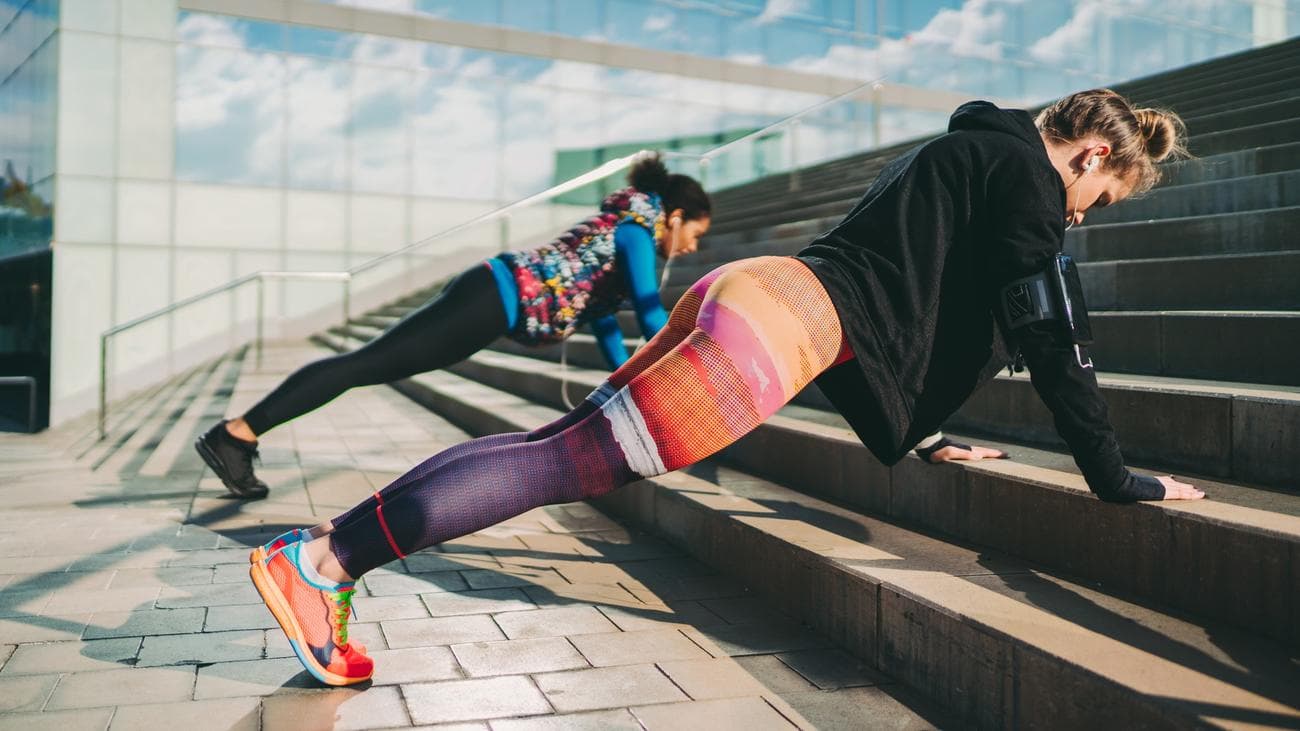 μια φωτογραφία δύο γυναικών που κάνουν πρέσες στις σκάλες