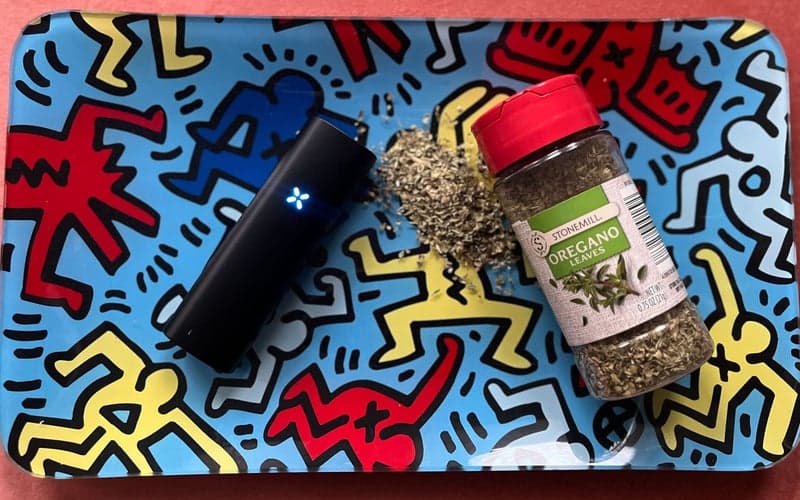 A Pax Plus cannabis vaporizer on a rolling tray with some oregano seasoning