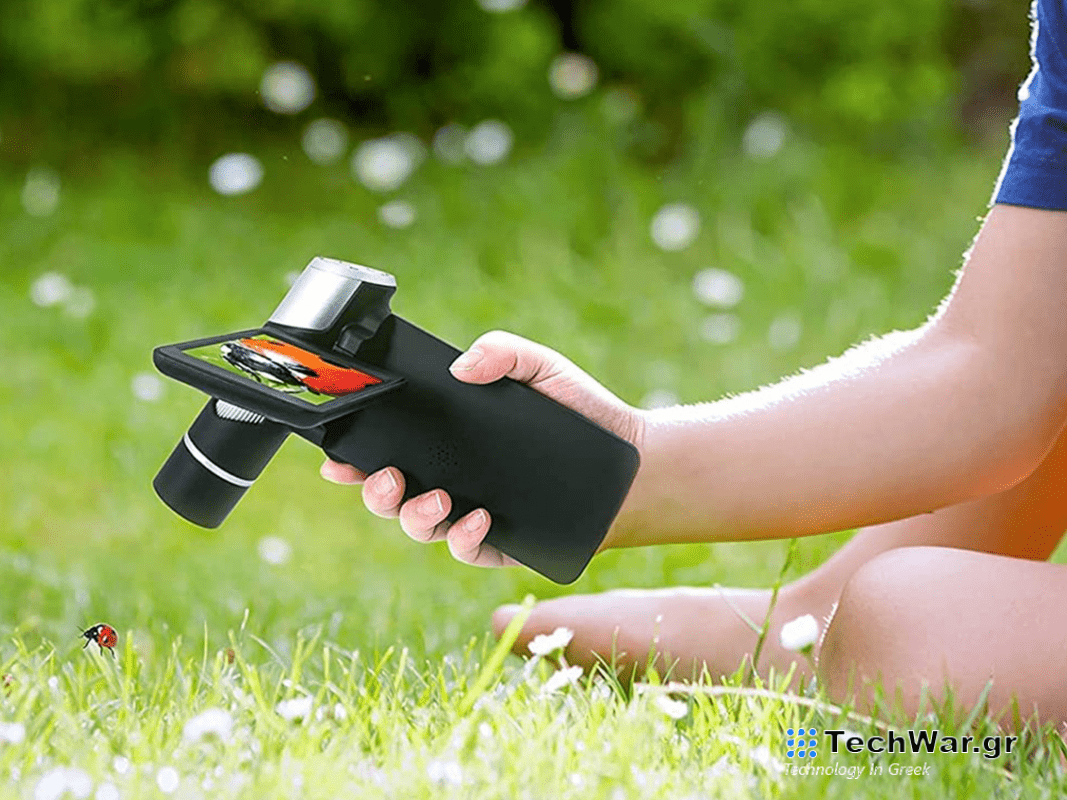 A person holding an LCD microscope in a backyard