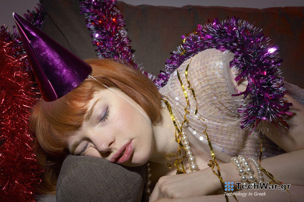 A woman wearing a party hat sand tinsel is sleeping on the sofa