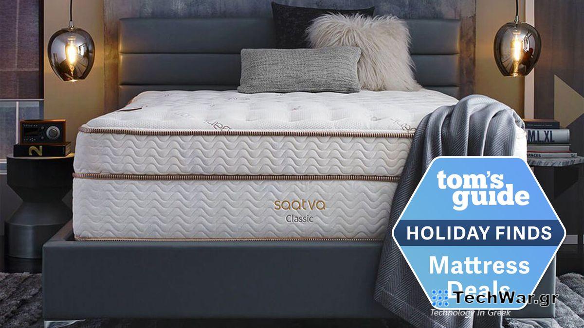 Image shows the Saatva Classic luxury innerspring hybrid mattress on a grey bedframe bookended by two brass pelmet lights