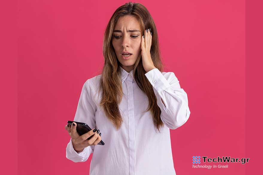 anxious young pretty caucasian girl puts hand head holding looking phone pink