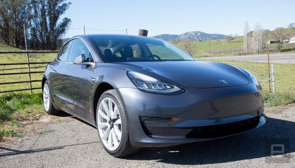 Το Tesla Model 3 κάθεται σε εξοχικό δρόμο.