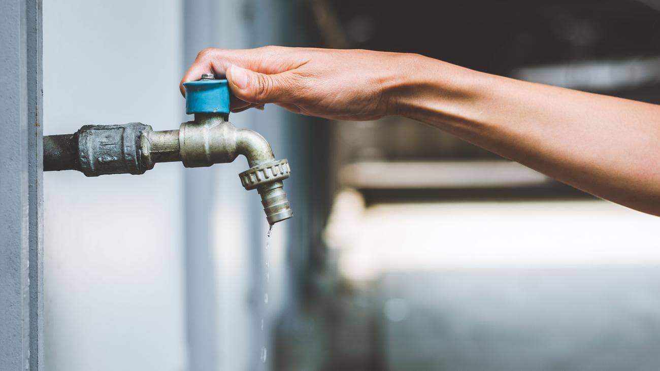 Ένα χέρι που κλείνει μια βρύση κήπου