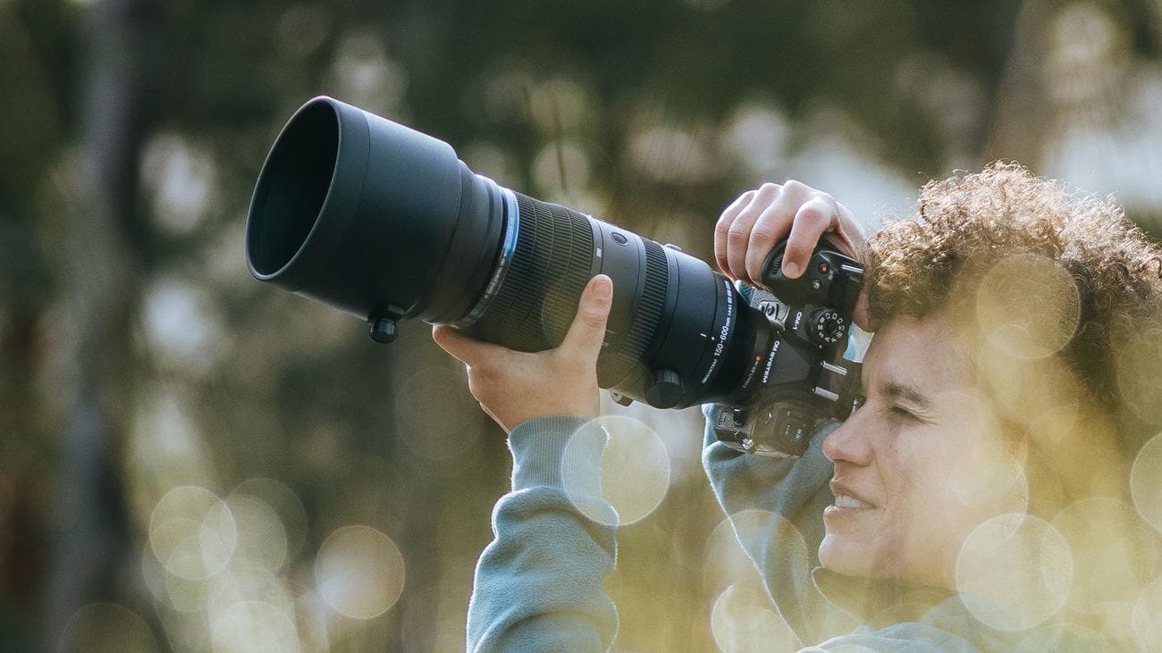 Φωτογράφος που κρατά το OM System OM-1 II με προσαρτημένο φακό M.Zuiko 150-600mm F5.0-6.3 IS
