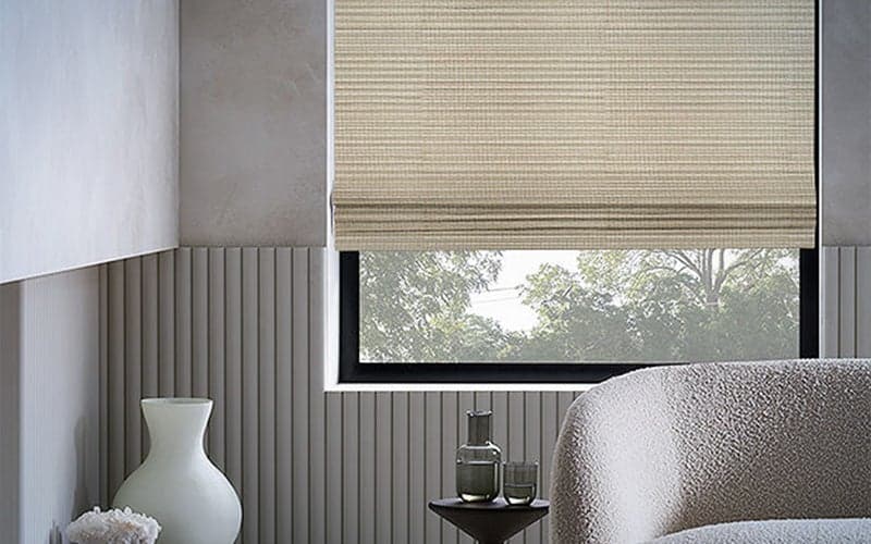 The best blackout shades for 2024 2 Shade Store Waterfall Woven Wood Shades behind neutral-toned furniture