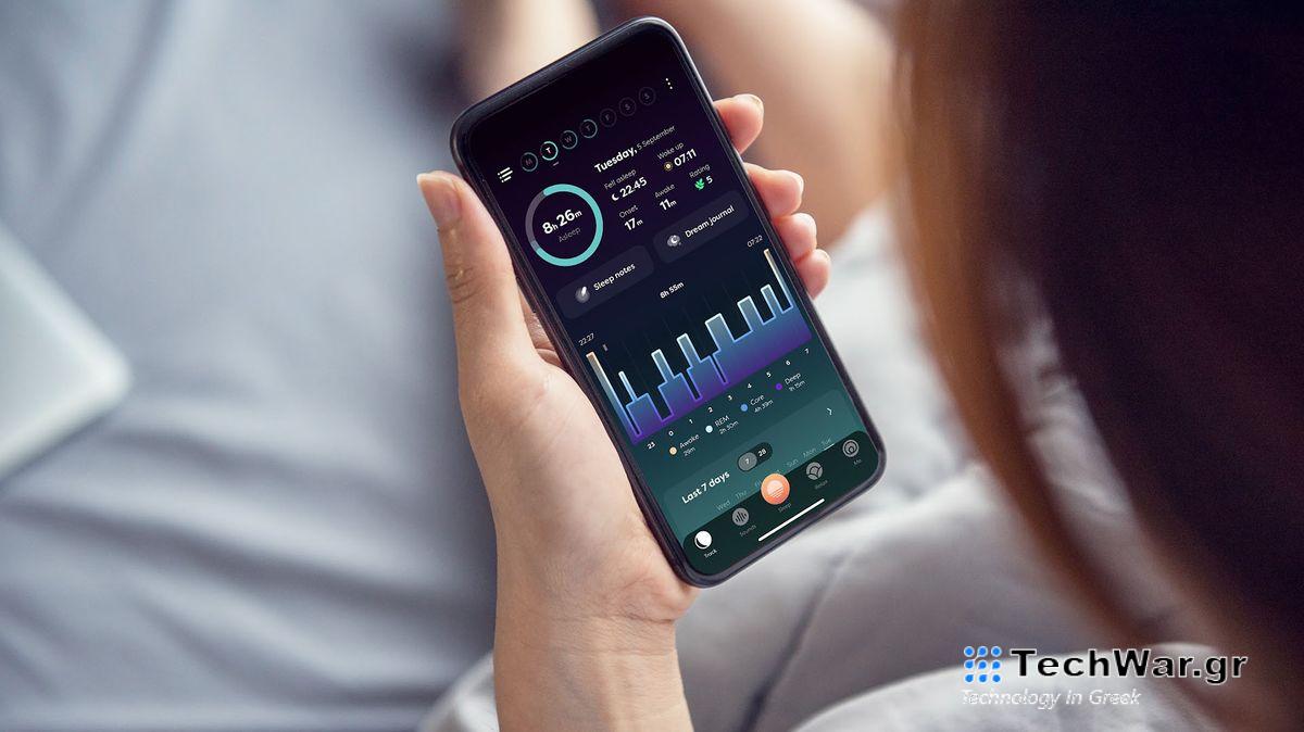A woman sitting in bed, checking the Sleepwave sleep tracker tab on her smartphone