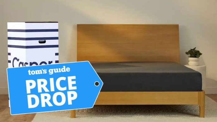 Το διαβάσατε σωστά — ο Casper πουλά ένα στρώμα Cal Casper Essential Mattress with a black cover photographed next to the cardboard box it ships in, with a price drop badge overlaid on the image