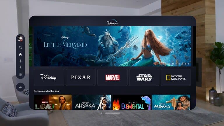 Εικόνα της εφαρμογής Disney+ για το VisionOS.  Ένα πλωτό παράθυρο δείχνει το αρχικό μενού της υπηρεσίας σε ένα σαλόνι.