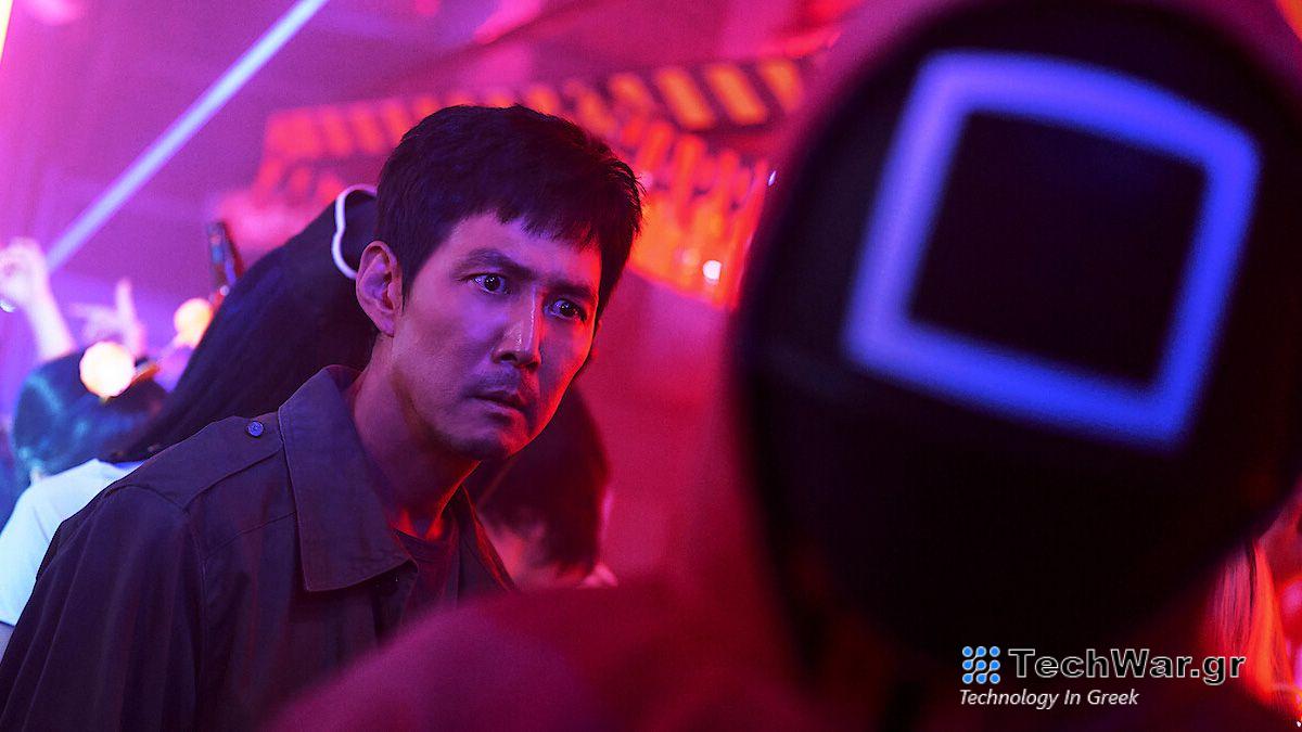A still from the TV series Squid Game (season 2) on Netflix of Lee Jung-jae as Seong Gi-hun surrounded by neon lights.