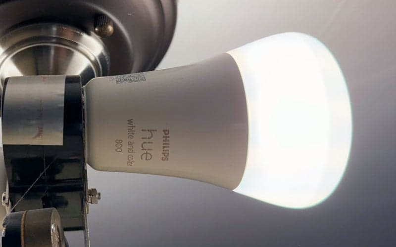 A Philips Hue light bulb screwed into a ceiling fan.