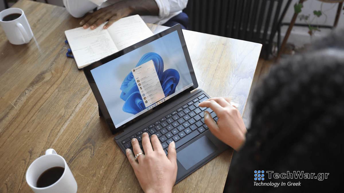 A woman at a table using a Windows laptop, opposite sits a man, neither show their face